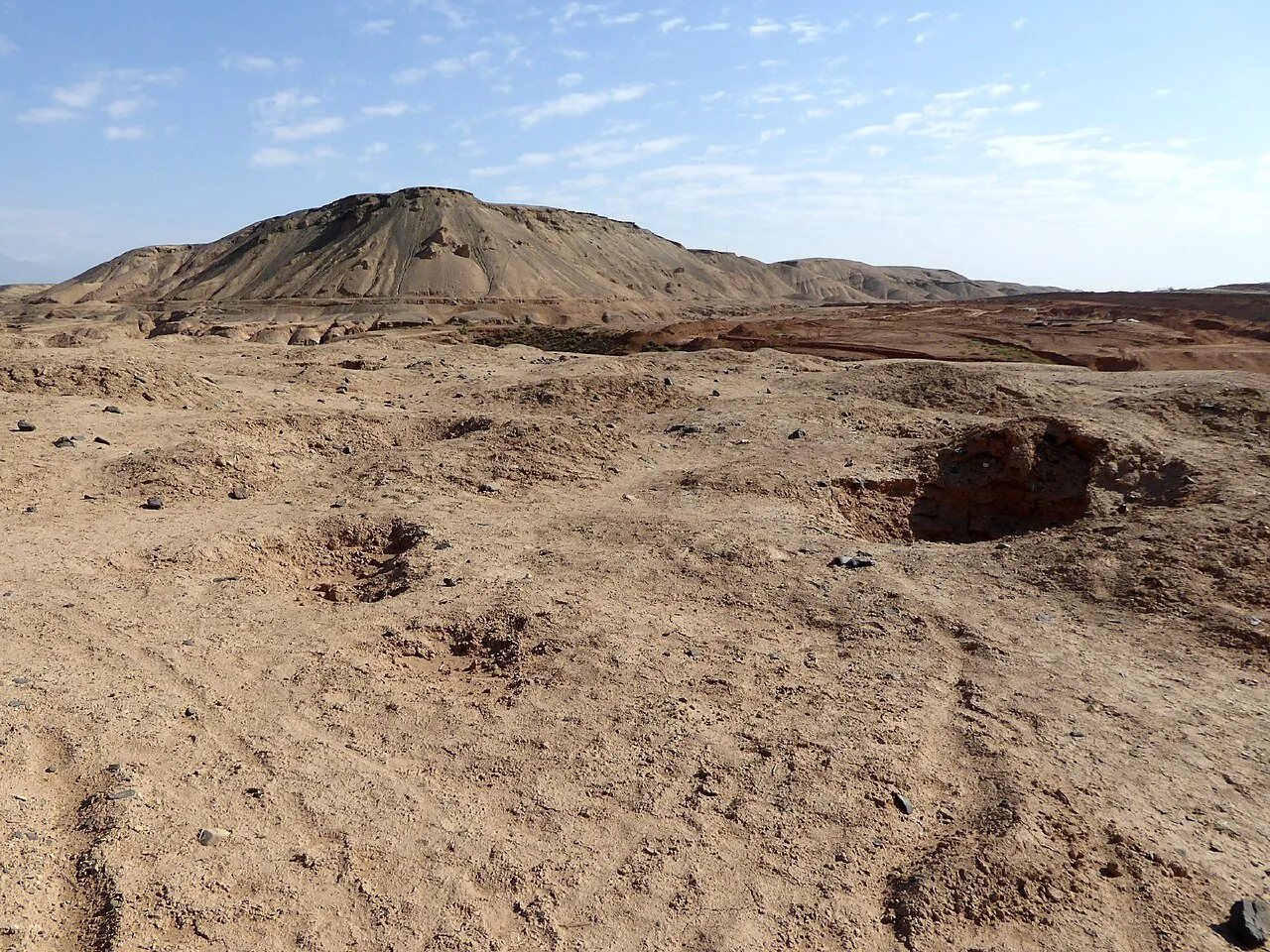 吐鲁番地区裸露的土色山地与遗址地貌，画面干燥辽阔