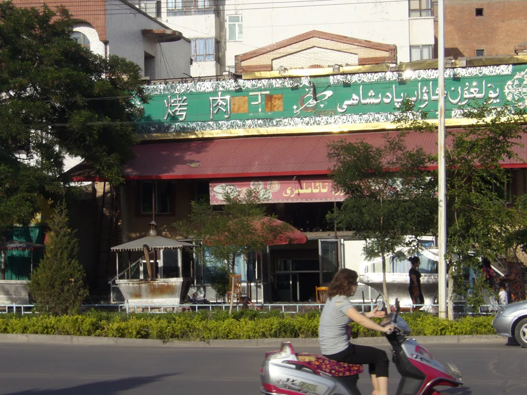 伊宁街头烤肉店与来往行人，呈现当地日常烟火气
