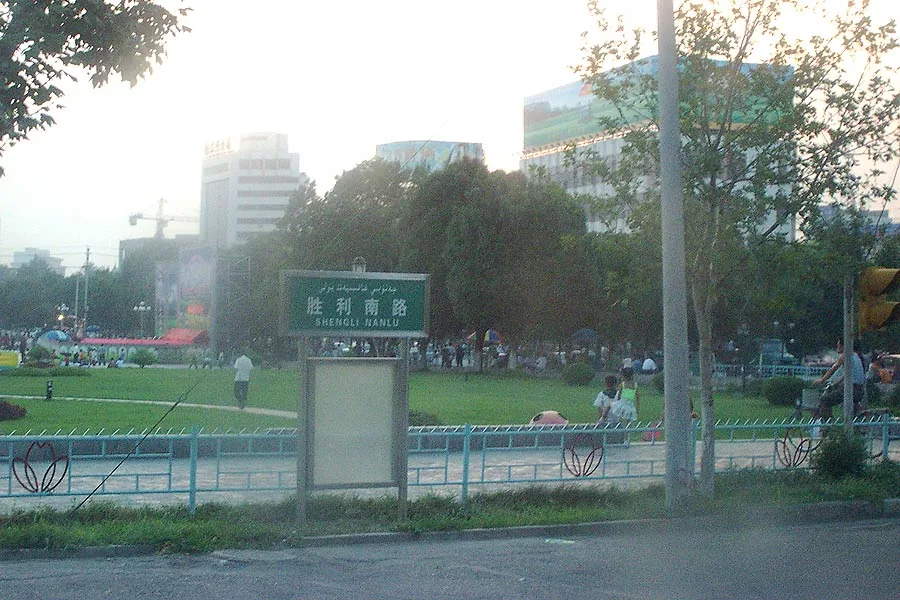 伊宁胜利南路与城市广场黄昏，灯光亮起，行人穿过街口
